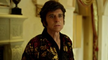 Movie still from “Behind the Candelabra” (2013), directed by Steven Soderbergh – A man in a black and gold jacket looking at the camera; Close Up shot, Low angle