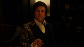 Movie still from “Behind the Candelabra” (2013), directed by Steven Soderbergh – A man in a suit holding a cigarette in his hand; Close Up shot, Over the shoulder angle