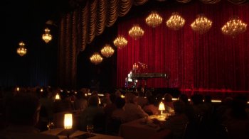 Movie still from “Behind the Candelabra” (2013), directed by Steven Soderbergh – People are sitting at tables in front of a stage; Extreme Wide shot, High angle