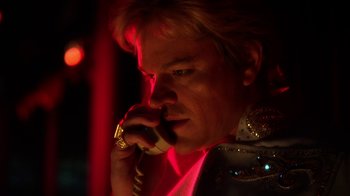 Movie still from “Behind the Candelabra” (2013), directed by Steven Soderbergh – A man talking on a phone in a dark room; Close Up shot, Low angle