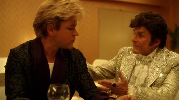Movie still from “Behind the Candelabra” (2013), directed by Steven Soderbergh – A man and a woman sitting at a dinner table talking to each other; Close Up shot, Over the shoulder angle