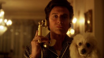 Movie still from “Behind the Candelabra” (2013), directed by Steven Soderbergh – A woman holding a phone and a dog; Close Up shot, Low angle