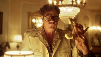 Movie still from “Behind the Candelabra” (2013), directed by Steven Soderbergh – A man with glasses is holding a phone; Close Up shot, Low angle
