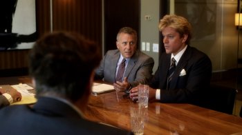 Movie still from “Behind the Candelabra” (2013), directed by Steven Soderbergh – A group of men sitting at a wooden table; Medium shot, Over the shoulder angle