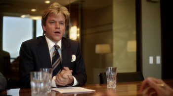 Movie still from “Behind the Candelabra” (2013), directed by Steven Soderbergh – A man sitting at a wooden table in front of two glasses; Close Up shot, Over the shoulder angle