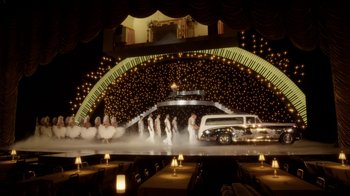 Movie still from “Behind the Candelabra” (2013), directed by Steven Soderbergh – A group of people in a stage with a limo; Extreme Wide shot, High angle