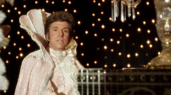 Movie still from “Behind the Candelabra” (2013), directed by Steven Soderbergh – A man dressed as a woman in front of a string of lights; Medium shot, Low angle