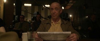 Movie still from “Being the Ricardos” (2021), directed by Aaron Sorkin – An older man sitting at a table reading a newspaper; Close Up shot, Over the shoulder angle