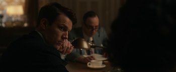 Movie still from “Being the Ricardos” (2021), directed by Aaron Sorkin – A man sitting at a table in front of two other men; Medium shot, Over the shoulder angle