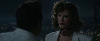 A woman wearing a white jacket with a rose in her neck