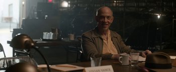 Movie still from “Being the Ricardos” (2021), directed by Aaron Sorkin – An older man sitting at a table with a cup of coffee in front of him; Medium shot, Over the shoulder angle