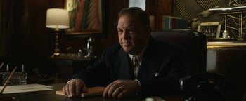 Movie still from “Being the Ricardos” (2021), directed by Aaron Sorkin – An older man sitting at a desk in a suit and tie; Medium shot, Low angle