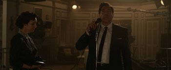 Movie still from “Being the Ricardos” (2021), directed by Aaron Sorkin – A man wearing a suit and tie holding a microphone; Medium shot, Low angle