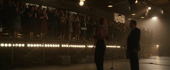 Movie still from “Being the Ricardos” (2021), directed by Aaron Sorkin – A woman standing in front of a microphone in front of a crowd of onlookers; Wide shot, Over the shoulder angle