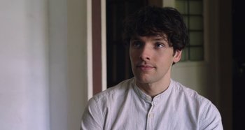 A man with a beard and a white shirt is looking to his left