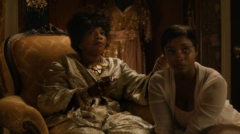 Movie still from “Bessie” (2015), directed by Dee Rees – Two women sitting on a couch in front of a mirror; Medium shot, Over the shoulder angle