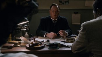 Movie still from “Bessie” (2015), directed by Dee Rees – A man sitting at a table in front of a camera; Close Up shot, High angle