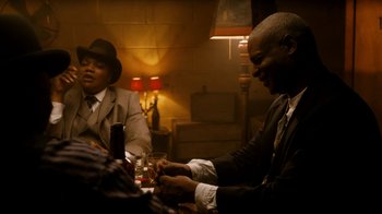 Movie still from “Bessie” (2015), directed by Dee Rees – Two men sitting at a table with a glass of wine; Medium shot, Low angle