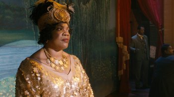 Movie still from “Bessie” (2015), directed by Dee Rees – An older woman wearing a gold dress and a feather headdress; Medium shot, Over the shoulder angle