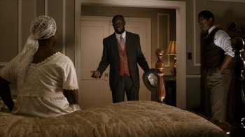 Movie still from “Bessie” (2015), directed by Dee Rees – A man in a suit standing in front of a woman; Medium shot, Over the shoulder angle