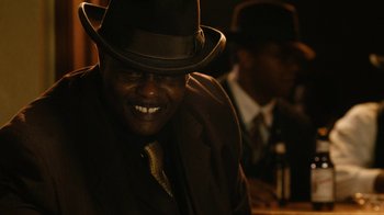 Movie still from “Bessie” (2015), directed by Dee Rees – A man wearing a hat and a suit and tie; Close Up shot, Low angle
