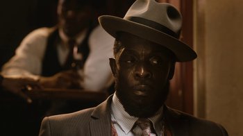 Movie still from “Bessie” (2015), directed by Dee Rees – A man in a suit and a hat is sitting in front of another man in a suit; Close Up shot, Over the shoulder angle
