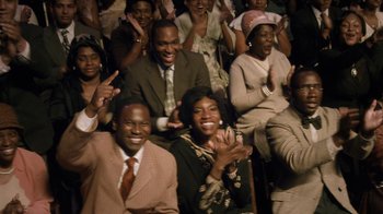 Movie still from “Bessie” (2015), directed by Dee Rees – A group of men and women sitting in front of each other clapping; Medium shot, High angle