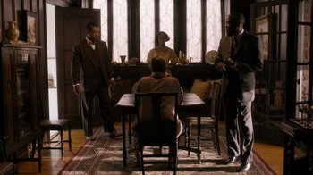 Movie still from “Bessie” (2015), directed by Dee Rees – A group of people standing around a table; Wide shot, High angle