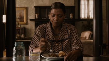 Movie still from “Bessie” (2015), directed by Dee Rees – An older woman sitting at a table with a plate of food in front of her; Close Up shot, Over the shoulder angle