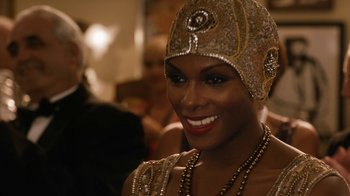 Movie still from “Bessie” (2015), directed by Dee Rees – A woman in a gold hat smiling for the camera; Close Up shot, Over the shoulder angle