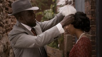 Movie still from “Bessie” (2015), directed by Dee Rees – A man putting a feather in a woman's hair; Close Up shot, Over the shoulder angle