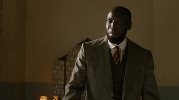 Movie still from “Bessie” (2015), directed by Dee Rees – A man in a suit and tie standing in a room; Close Up shot, Low angle