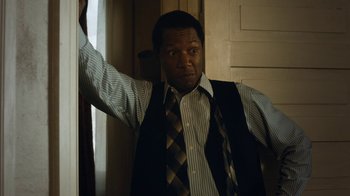 Movie still from “Bessie” (2015), directed by Dee Rees – A man wearing a vest and a striped shirt; Medium shot, Low angle