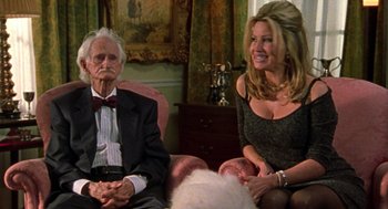Movie still from “Best in Show” (2000), directed by Christopher Guest – An older man and woman sitting next to each other in a living room; Medium shot, Over the shoulder angle