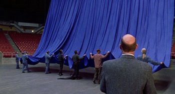 Movie still from “Best in Show” (2000), directed by Christopher Guest – A group of men standing next to each other holding up a blue curtain; Extreme Wide shot, High angle