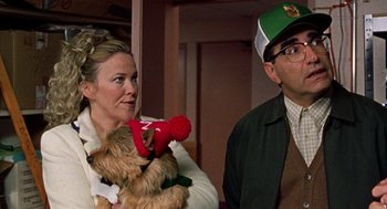 Movie still from “Best in Show” (2000), directed by Christopher Guest – A woman holding a stuffed animal next to a man wearing glasses; Medium shot, Over the shoulder angle