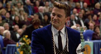 Movie still from “Best in Show” (2000), directed by Christopher Guest – A man in a blue jacket and a black and white polka dot tie; Close Up shot, Over the shoulder angle