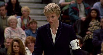 Movie still from “Best in Show” (2000), directed by Christopher Guest – A woman in a crowd of people wearing a black jacket; Close Up shot, Low angle
