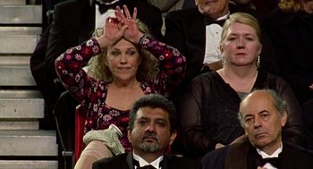 Movie still from “Best in Show” (2000), directed by Christopher Guest – A woman claps her hands while sitting in a crowd; Medium shot, High angle