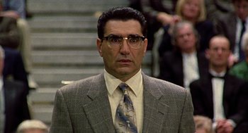 Movie still from “Best in Show” (2000), directed by Christopher Guest – A man in a suit and tie standing in front of a crowd of onlookers; Close Up shot, Low angle