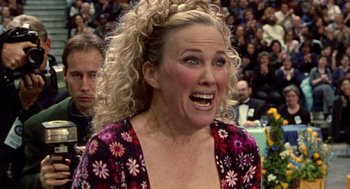 Movie still from “Best in Show” (2000), directed by Christopher Guest – A woman with blonde curly hair and a pink and white floral shirt; Close Up shot, Low angle