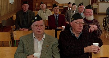 Movie still from “Best in Show” (2000), directed by Christopher Guest – A group of men sitting next to each other in a room; Medium shot, High angle
