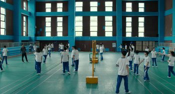 Movie still from “Better Days” (2019), directed by Derek Tsang – A group of people standing in a gymnasium; Extreme Wide shot, High angle