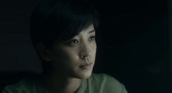A woman with short black hair is looking to her left