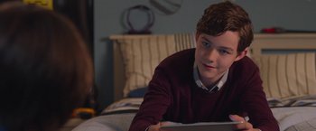 Movie still from “Better Watch Out” (2016), directed by Chris Peckover – A young man sitting on top of a bed with a computer; Medium shot, Over the shoulder angle