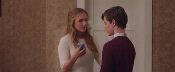 Movie still from “Better Watch Out” (2016), directed by Chris Peckover – A woman holding a cell phone in her hand while standing next to a boy; Medium shot, Over the shoulder angle