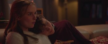 Movie still from “Better Watch Out” (2016), directed by Chris Peckover – A young man and a young woman sitting next to each other on a couch; Close Up shot, Over the shoulder angle