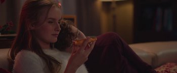 Movie still from “Better Watch Out” (2016), directed by Chris Peckover – A woman eating a piece of pizza while sitting on a couch; Close Up shot, Over the shoulder angle
