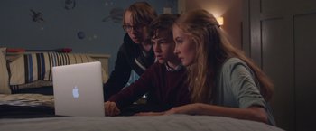 Movie still from “Better Watch Out” (2016), directed by Chris Peckover – A group of young people sitting on a bed looking at a computer; Medium shot, High angle