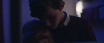 Movie still from “Better Watch Out” (2016), directed by Chris Peckover – A young boy holding a doll in his arms; Close Up shot, Over the shoulder angle